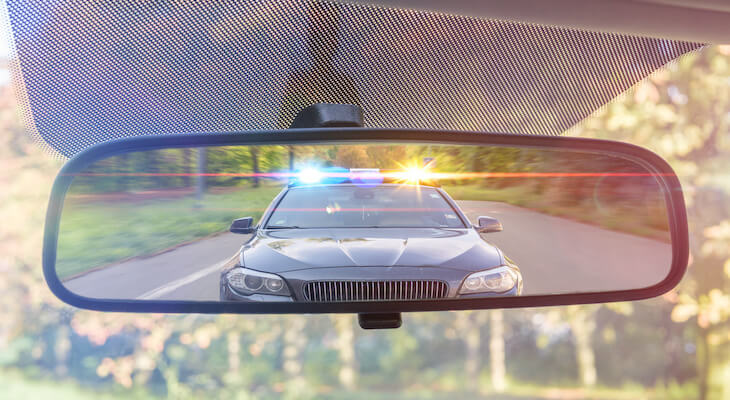 Cheap car insurance in KY: police car seen in a car's rearview mirror
