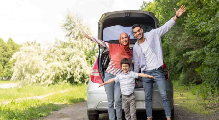 parents and child standing in front of their vehicle smiling