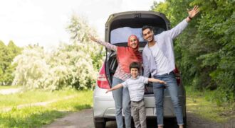 family standing in front of their vehicle and smiling