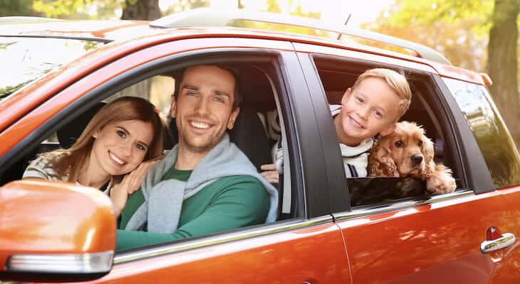 Family happily looking at the camera while sitting inside their car