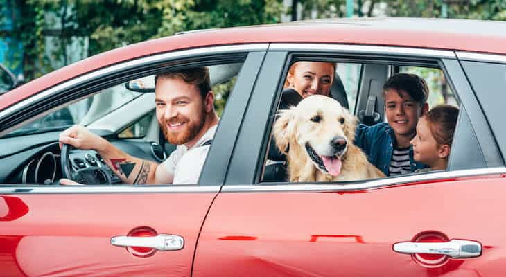 Car insurance for families: happy family going on a road trip with their dog
