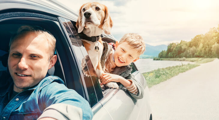 Happy family with their dog traveling in their car