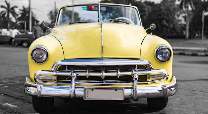 The front view of a yellow classic car with the background in black and white