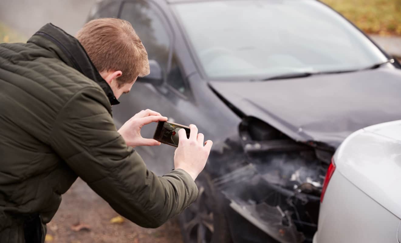 man taking a photo at scene of car accident