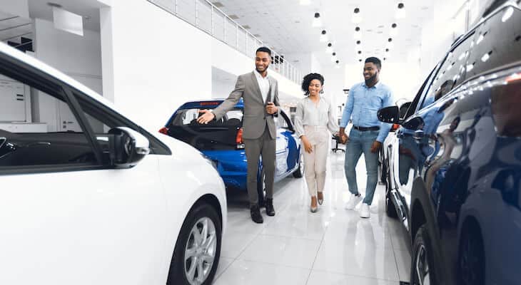 Car salesperson showing different cars to potential customers
