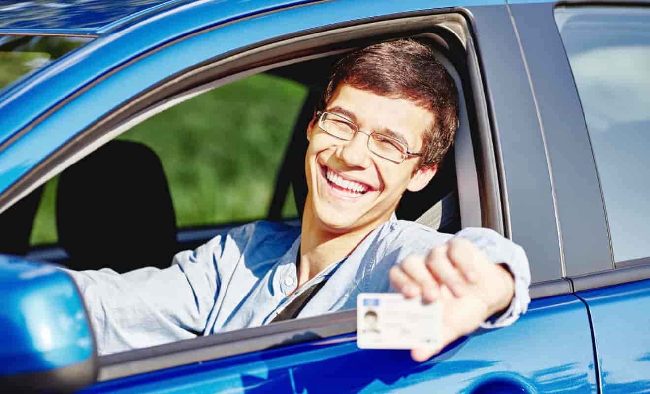 teen driver holding license in car