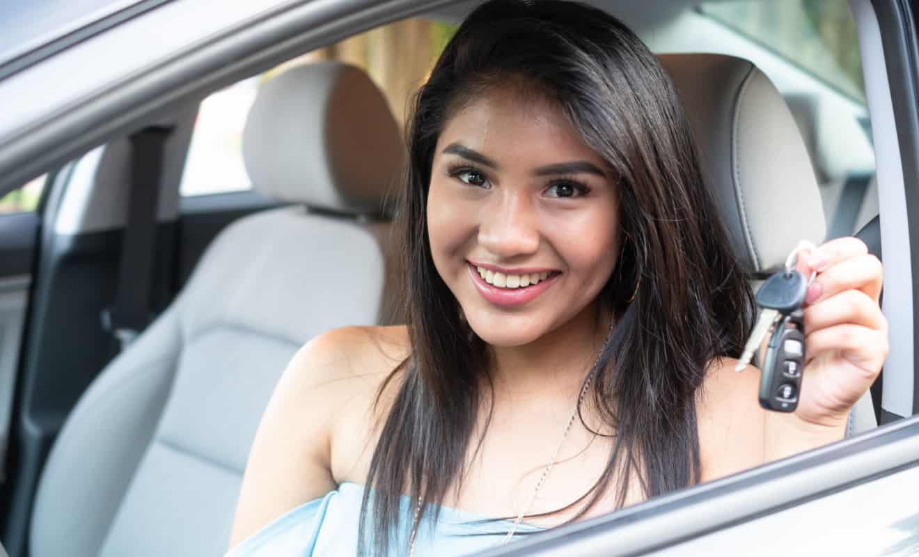 teen driver smiling while holding her keys in the car