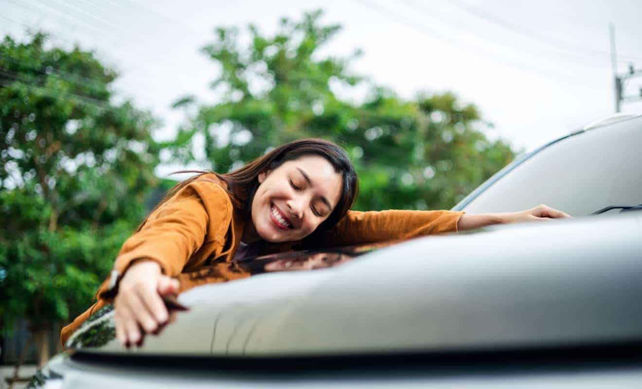 woman smiling with her vehicle covered with short term car insurance