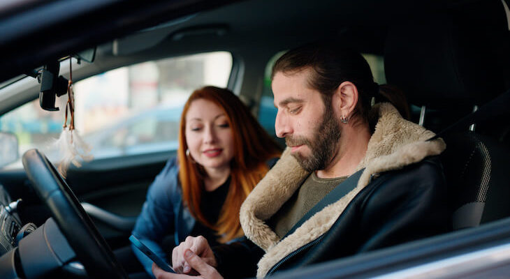 Couple using a phone while sitting inside a car