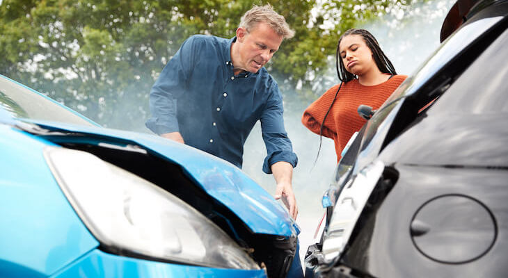 A man and a woman checking the damage to their cars that crashed into each other and they need the best liability car insurance