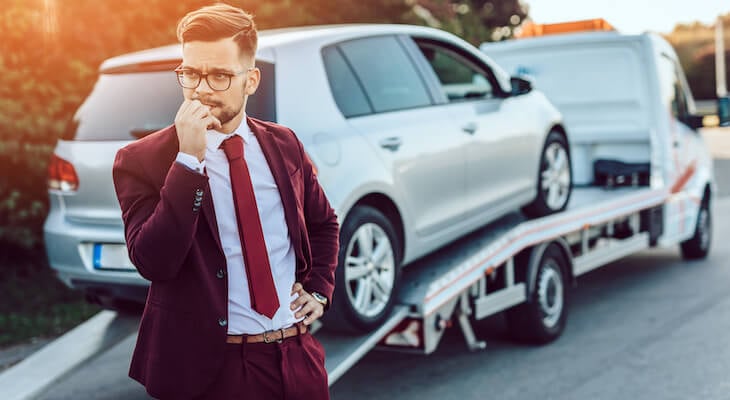 Stressed man with his car on a flat bed hoping he has the best car insurance for full coverage