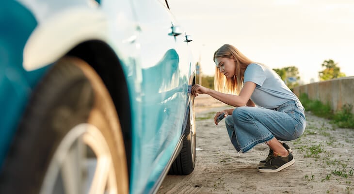 Young woman checking her cars tires