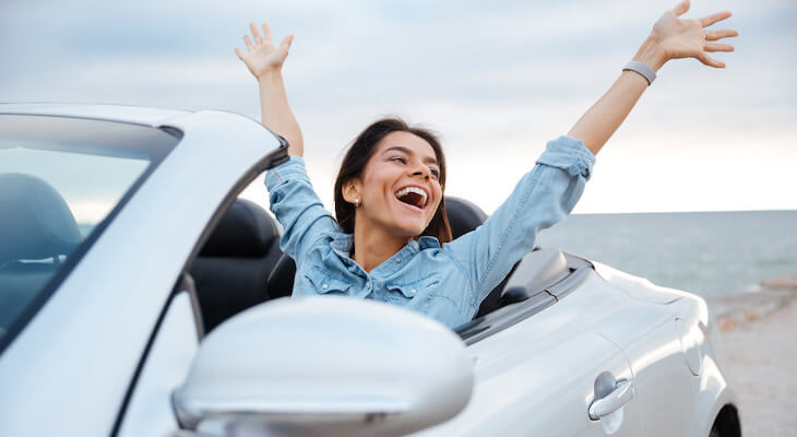 A happy woman behind the wheel of her convertible having the best car insurance Virginia drivers can get