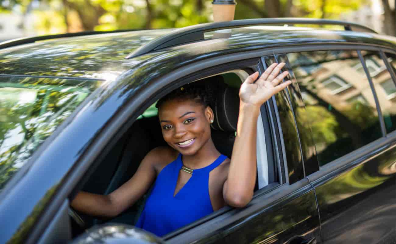 woman smiling and waving while driving car