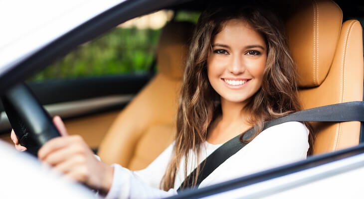 Low income car insurance: woman smiling at the camera while sitting in her car