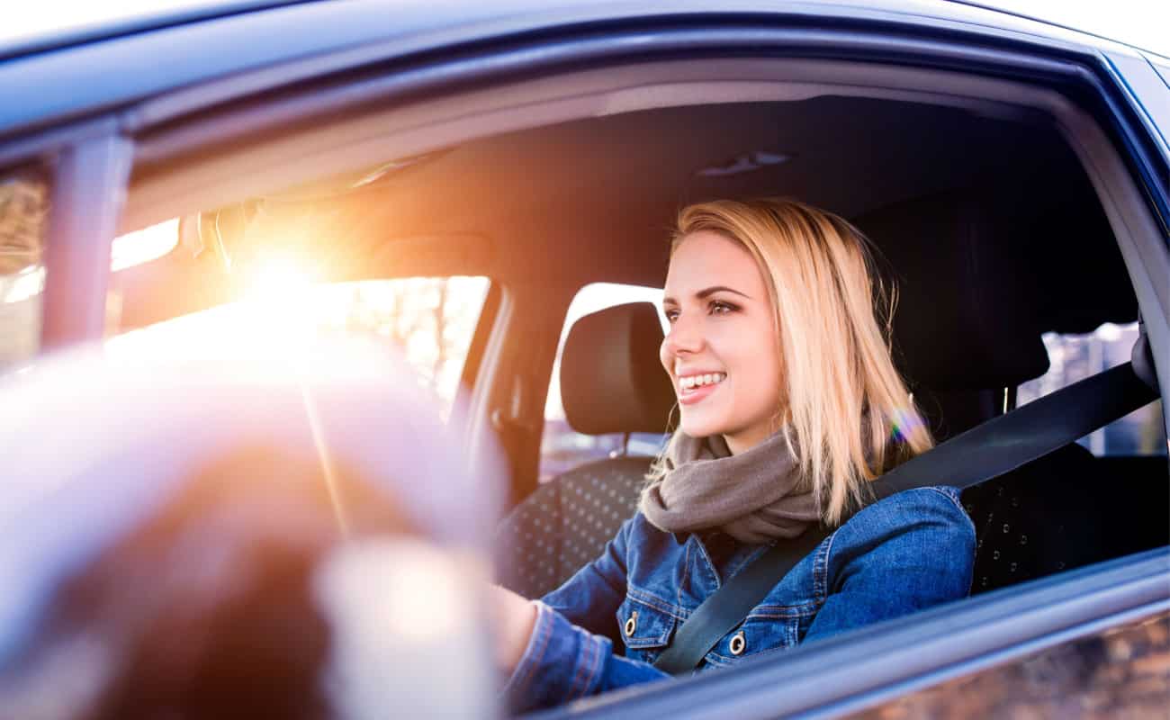 young woman smiling while driving her car