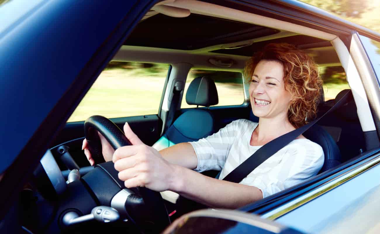 50 year old woman smiling while driving her car