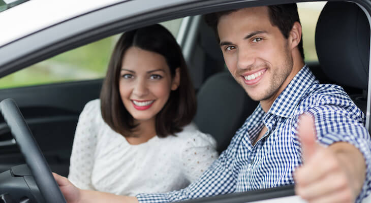 Car insurance married vs single: couple giving us the thumbs-up while sitting in their car