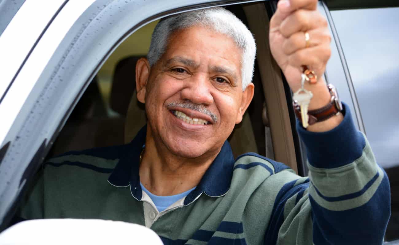 elderly man in the car smiling while holding his car keys