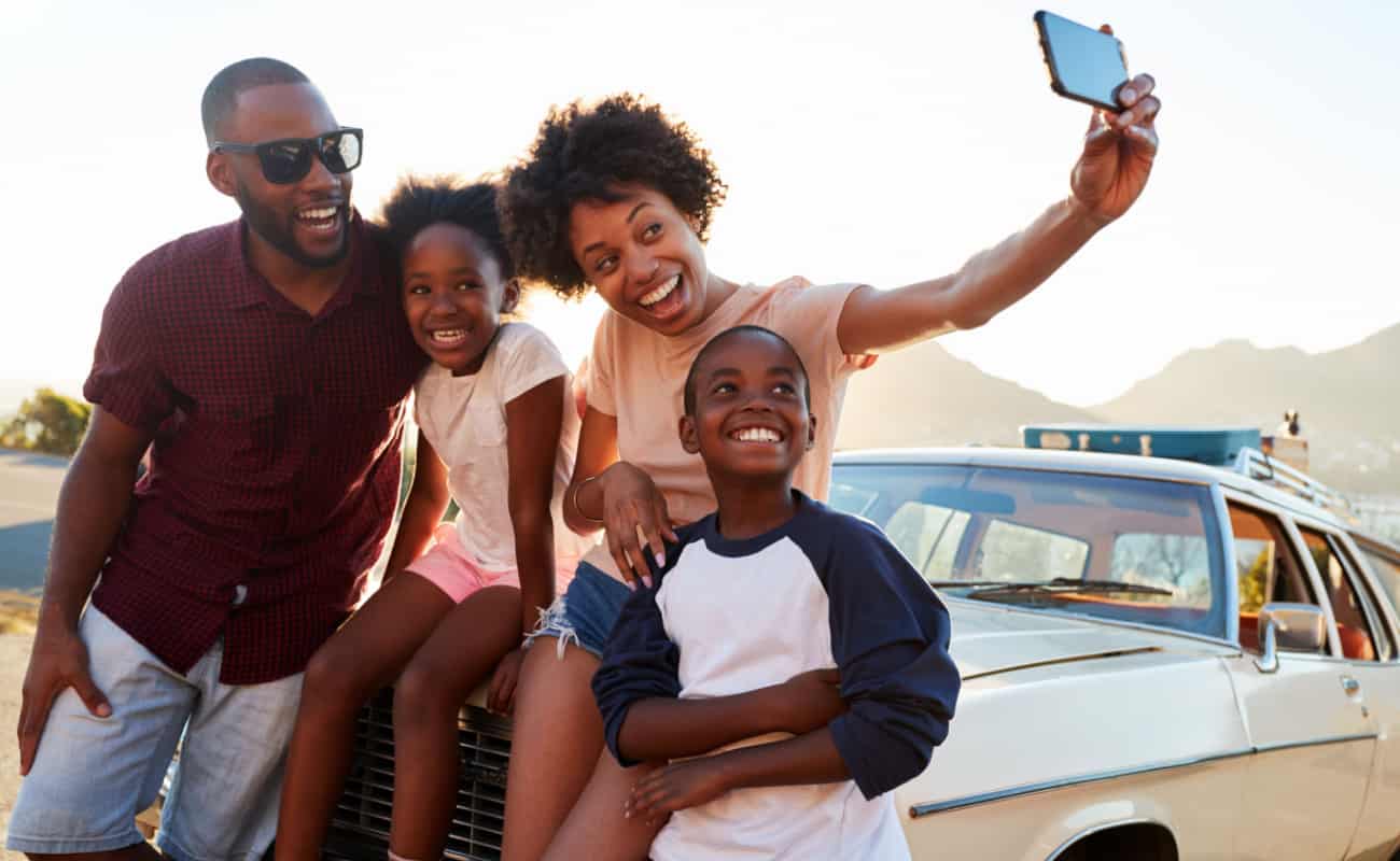 family taking a photo beside their car