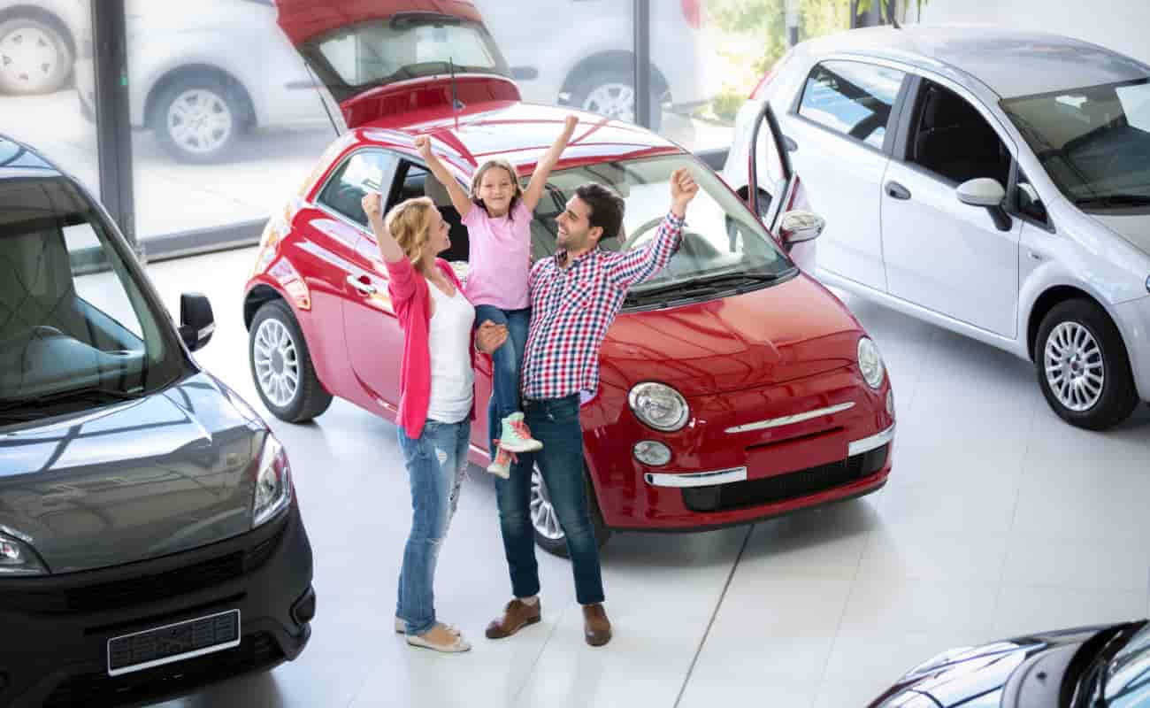 family excited at car dealership because they bought a new car