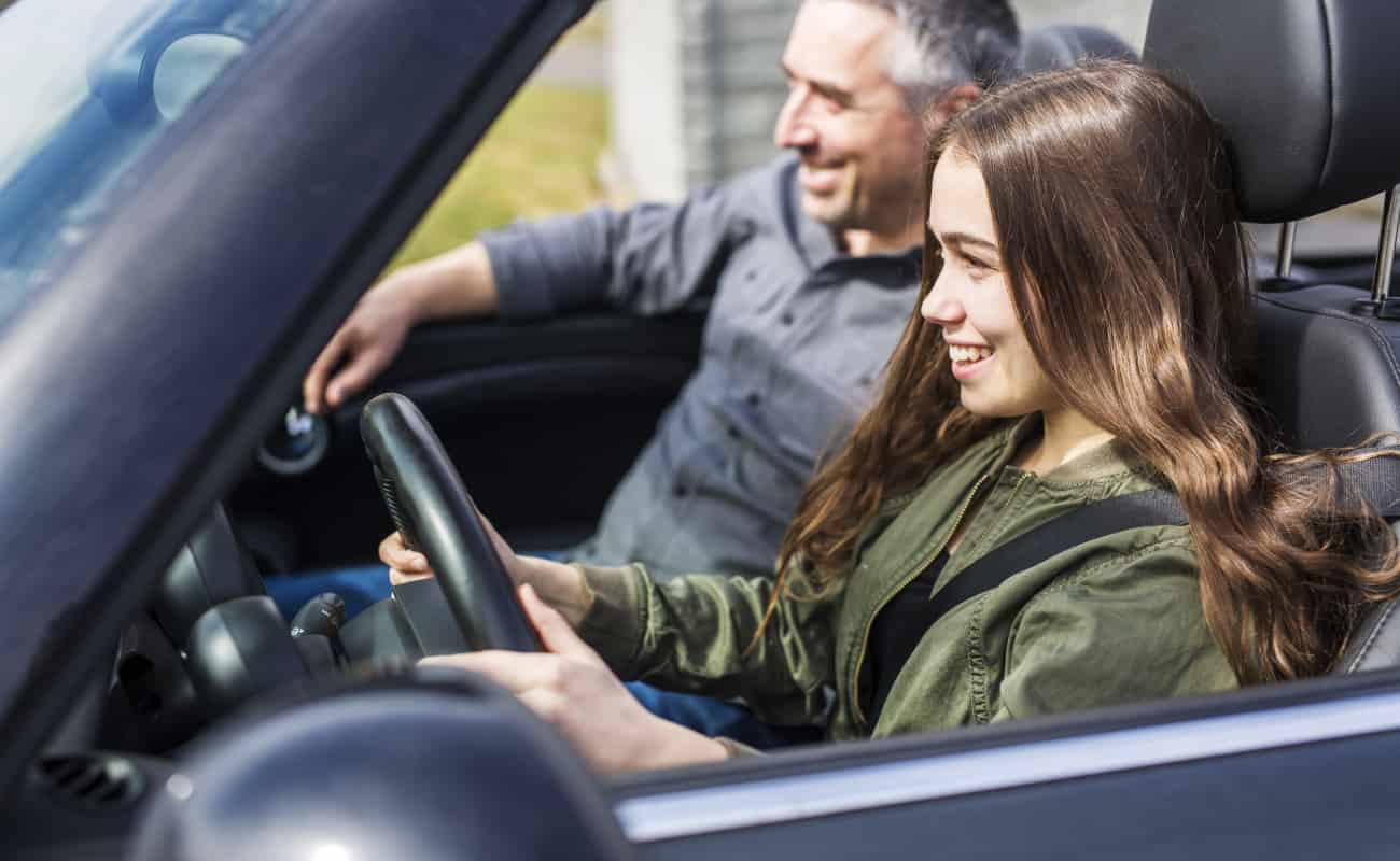 teen girl driving the car with her dad