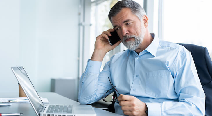 Entrepreneur talking on the phone while looking at a laptop