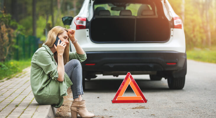 What is towing and labor coverage: woman talking on the phone while sitting on the pavement