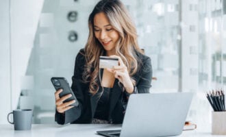 Automatic payments discount: entrepreneur using her phone while holding a credit card