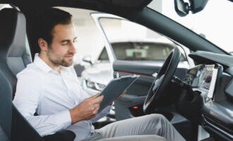 Man sits in a car looking at a tablet