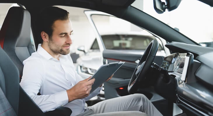 Man sits in a car looking at a tablet
