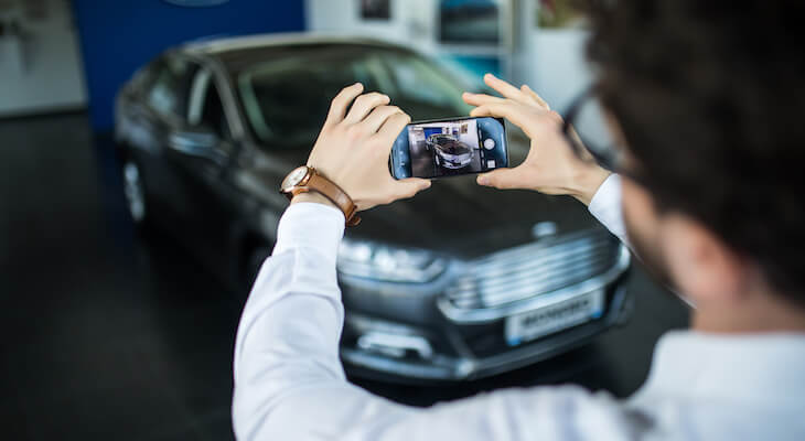 Man takes photo of a vehicle in a showroom