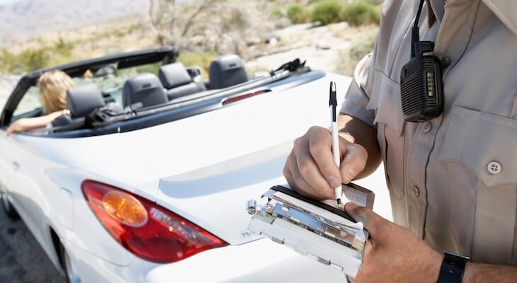 Factors that affect car insurance rates: police officer writing a traffic ticket