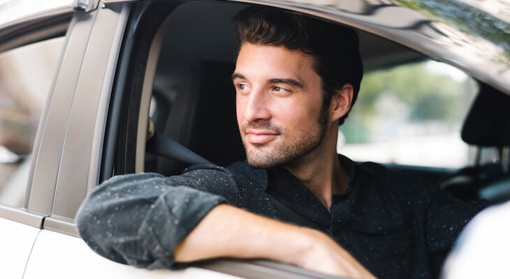 Man sitting in his car while looking out the window