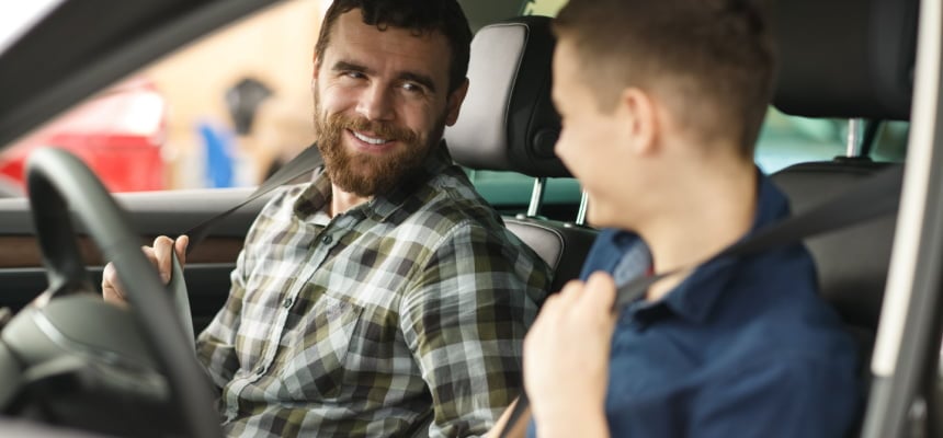 man talking to his young son who is learning to drive