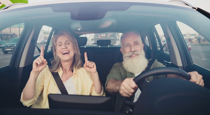 Elderly couple happily driving their car