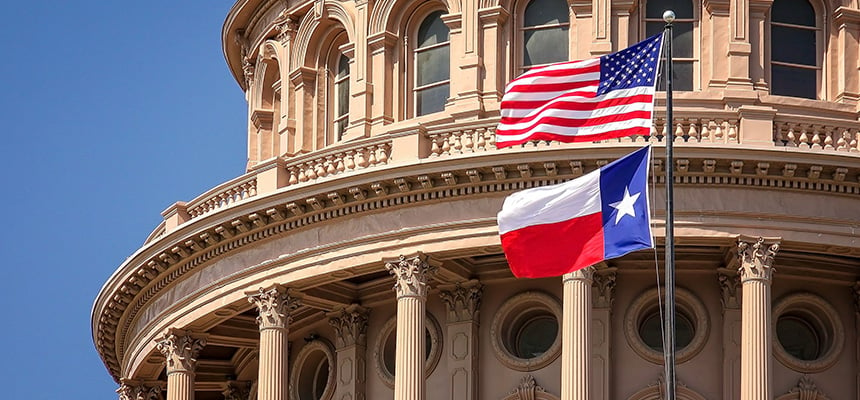 American and Texas state flags flying on the dome of the Texas State Capitol building