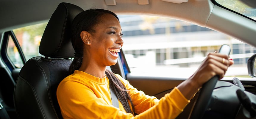 Black woman in a yellow shirt driving