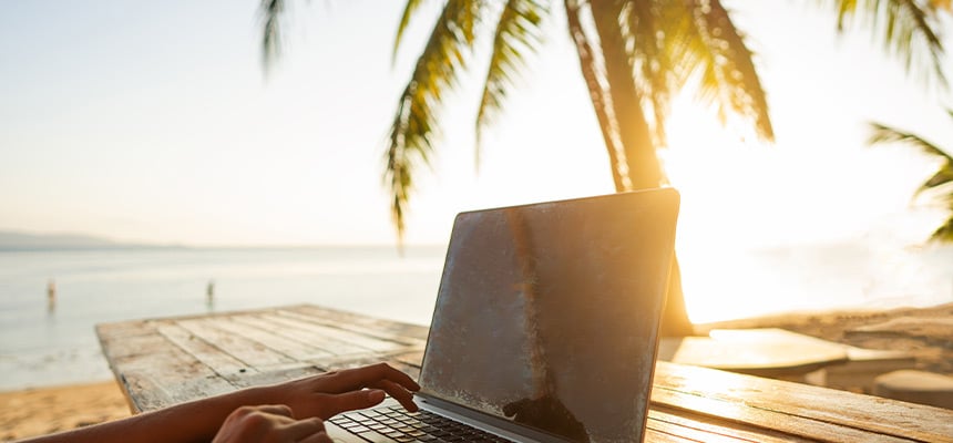 person on a computer in a tropical location