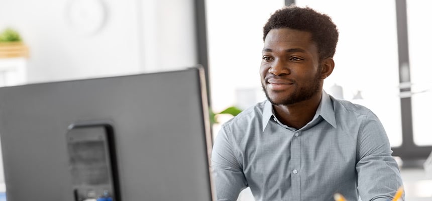 black man in grey shirt looking at computer