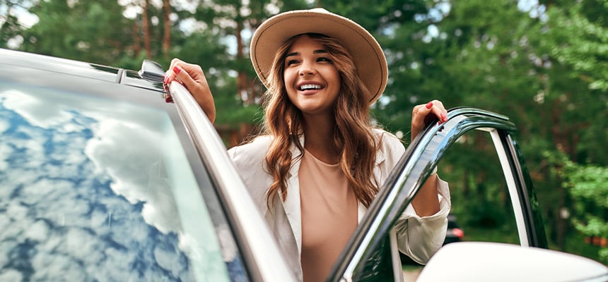 white woman with large hat smiling getting out of car