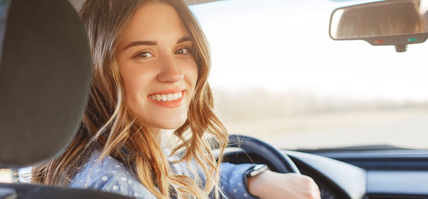young white woman driving in a blue shirt