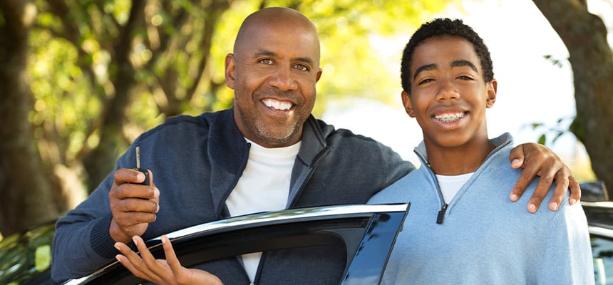 Teen and parent smiling outside their car