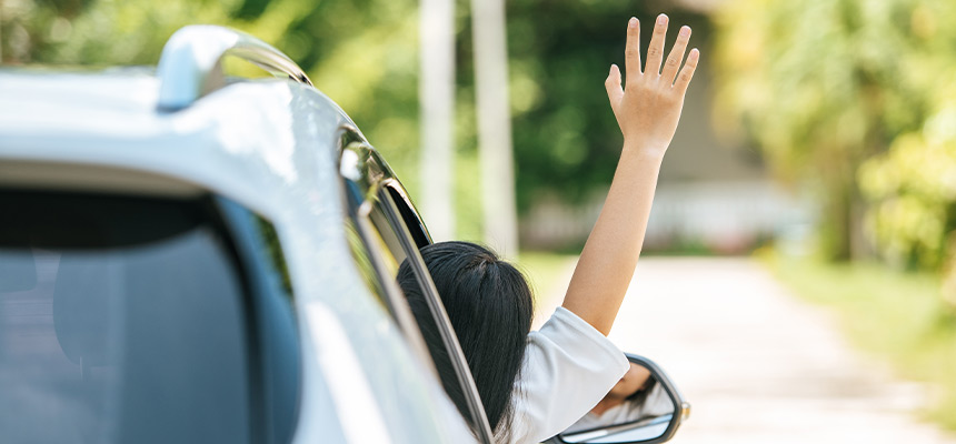 Woman waving her hand out of the window of a car