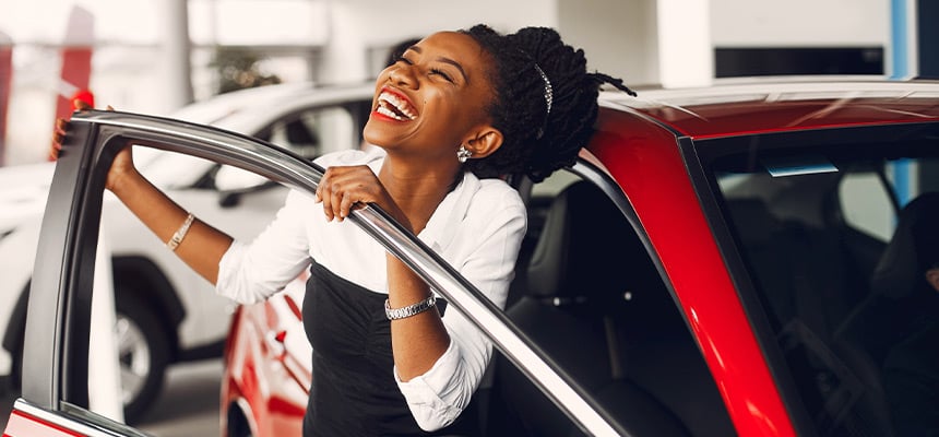 black woman smiling with a red car