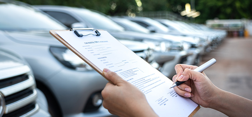 person signing a car purchasing document on a clip board