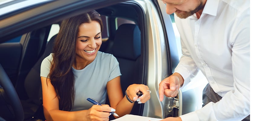 woman sign new car paperwork