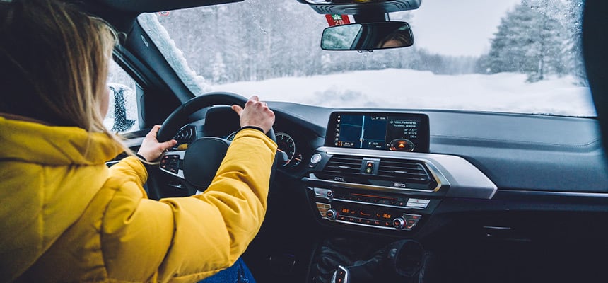 Woman driving down a snowy Alaskan road