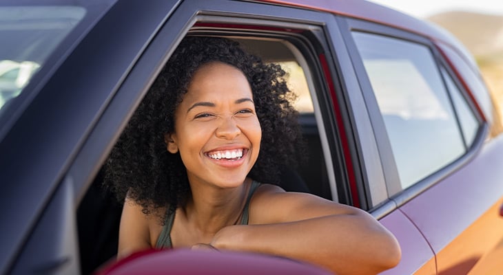 Smiling woman looks outside of the front car window