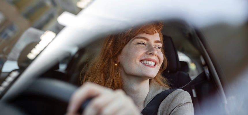 A woman smiling driving an electric vehicle